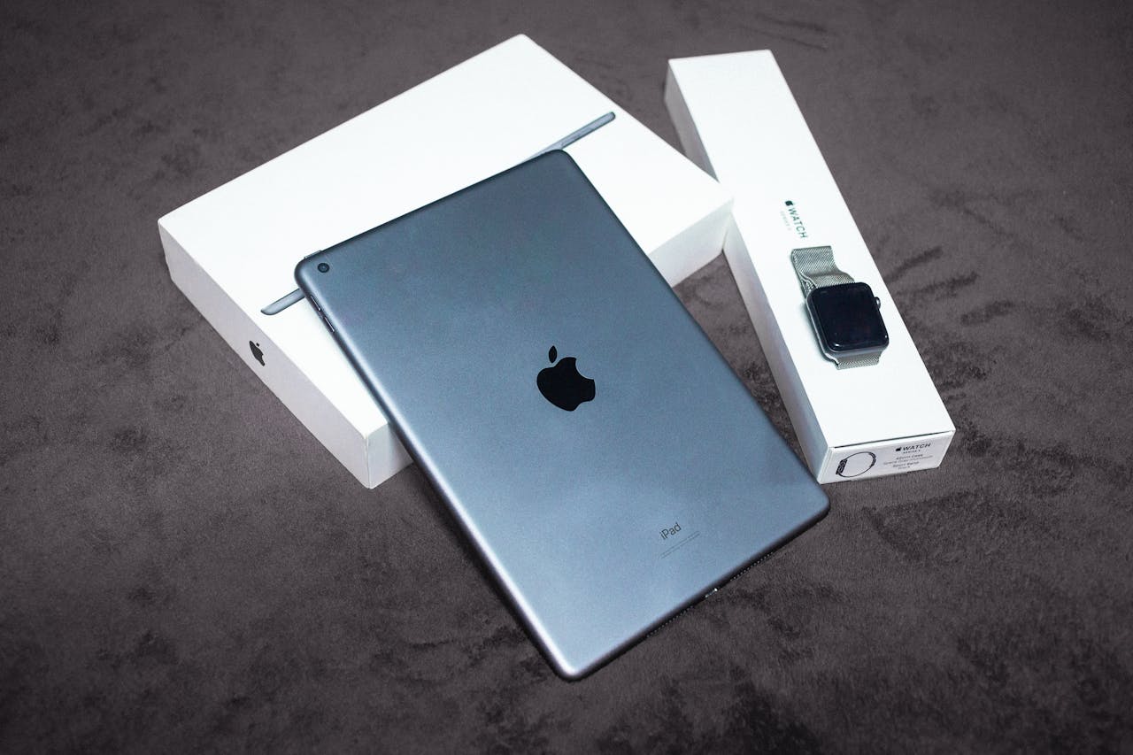 iPad and Apple Watch displayed on a black background, highlighting sleek design and packaging.